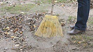 Woman sweeping the leaves with broom in the park