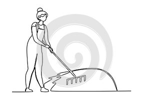 A woman sweeps the garden with a rake