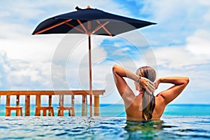 Woman swim in beach infinity pool with sea view