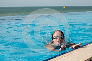 Woman in a swim glasses in a pool with sea view