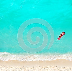 Woman swim with matrass in the water on beach