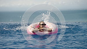 Woman swim and smile with inflatable donut ring with water splash