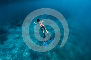 Woman swim underwater with fins. Freediving in ocean