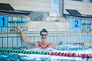 Woman swimmer happy at the finish in the pool