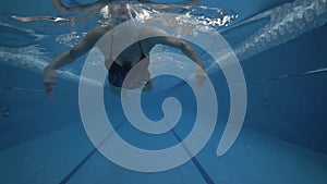 Woman swimmer swimming breaststroke in waterpool underwater view