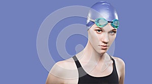 Woman swimmer in swimming cap and goggles on her head look at the camera on an isolated background