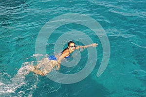 Woman swimmer swimming crawl in blue sea. Woman swiming in the sea. Happy young woman in a blue swimsuit in the sea on vacation.