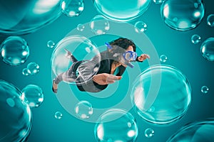 Woman swimming among air bubbles with mask and snorkel in a deep turquoise background