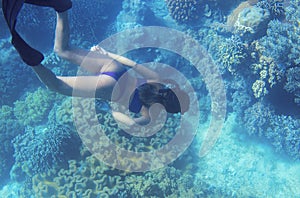 Woman swimming in blue water. Freediver and coral reef landscape. Tropical island lagoon snorkeling and diving