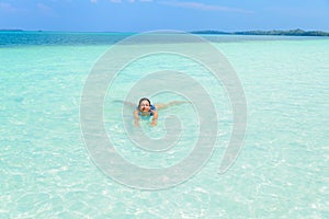 Woman swimming in caribbean sea turquoise transparent water. Tropical beach in the Kei Islands Moluccas, summer tourist