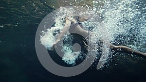 A woman swimming and diving underwater in a natural pool with pristine water