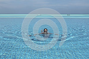 Woman swimming in infinity pool in Maldives