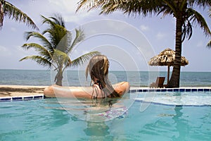 Woman swimming in infinity pool beside ocean