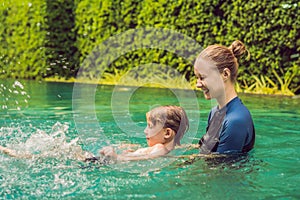 Woman swimming instructor for children is teaching a happy boy to swim in the pool photo