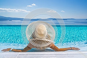 Woman at the swimming pool on the island of Santorini in Greece with view on the calde photo