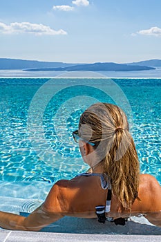 Woman at the swimming pool on the island of Santorini in Greece with view on the calde photo