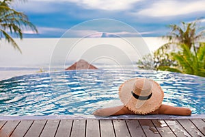 Woman in the swimming pools with the summer hat look at the sea with blue sky in front of her. Summer concept