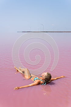 Woman swimming in salt plains waters colored with pink algae