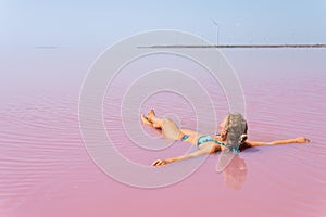 Woman swimming in salt plains waters colored with pink algae