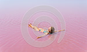 Woman swimming in salt plains waters colored with pink algae