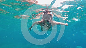 Woman in a swimming suit freediving at the depth of the sea.