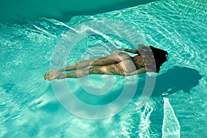 Woman swimming underwater in a blue pool