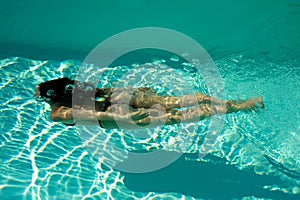 Woman swimming underwater in a blue pool