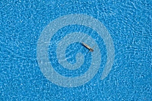 Woman swimming underwater in a pool, top view