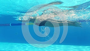 Woman is swimming underwater in pool during triathlon training