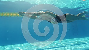 Woman is swimming underwater in pool during triathlon training