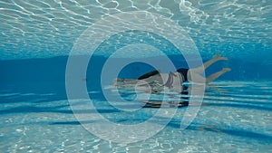 Woman swimming underwater in slow motion in pool