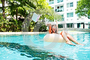 Woman swims in the swimming pool in the pool and throws the laptop into the water. The girl is resting on the sea on an