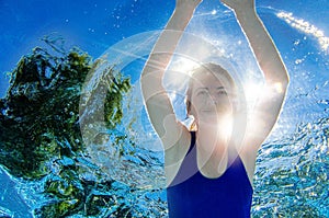 Woman swims underwater in swimming pool, healthy active girl dives and has fun under water, fitness and sport on vacation photo