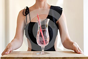 woman in swimsuit holding coctail glass with straw at table. Fruit lemonade healthy drinking beverage Close