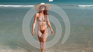 Woman in swimsuit and large hat emerges from sea with a wide, radiant smile. Female smile radiates happiness and