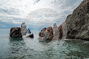 Woman swimsuit sea. Attractive blonde woman in a black swimsuit enjoying the sea air on the seashore around the rocks