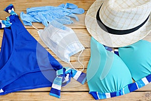 woman swimsuit, sun hat and medical mask on wooden