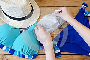 woman swimsuit, sun hat and medical mask on wooden