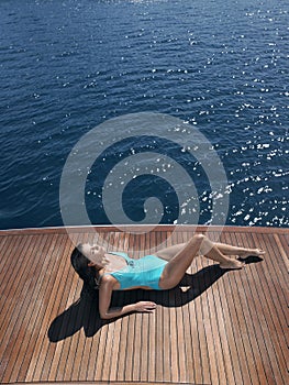 Woman In Swimsuit Sunbathing On Yacht's Floorboard