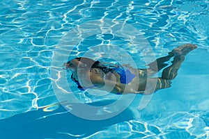 Woman with swimsuit swimming on a blue water pool. Underwater woman portrait with blue bikini in swimming pool