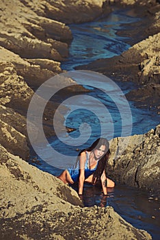 Woman in swimsuit in water stream in sand, vacation