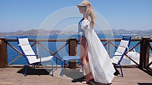 Woman in swimsuit white dress and straw hat on terrace with Sea View 4K