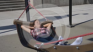 Woman swinging in hammock in modern park