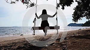 woman swinging on a wooden swing at sunset beach