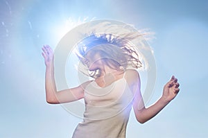 Woman swishing her hair outside infront of lensflare