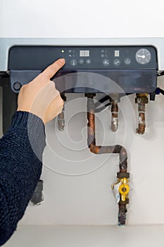 Woman switching on the heating boiler at home