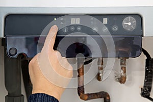 Woman switching on the heating boiler at home