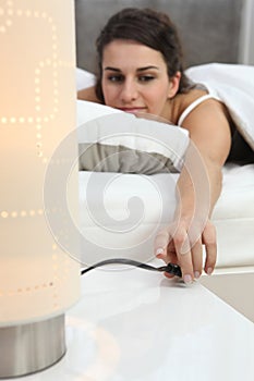 Woman switching off lamp