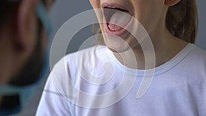 Woman with swollen glands coughing during otolaryngologist examination, close-up