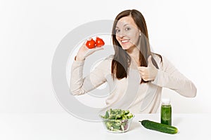 Woman at table with green detox smoothies, fresh salad in glass bowl, tomato, cucumber isolated on white background